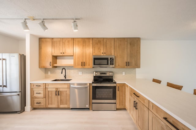 kitchen with sink, a breakfast bar area, backsplash, stainless steel appliances, and light wood-type flooring