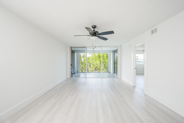 spare room featuring floor to ceiling windows, light hardwood / wood-style floors, and plenty of natural light