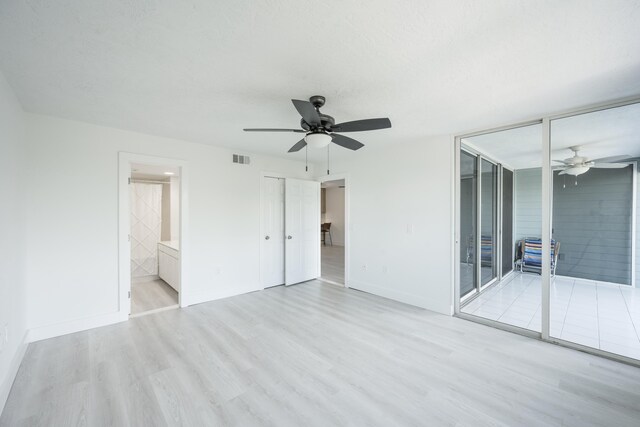 spare room featuring expansive windows, ceiling fan, and light wood-type flooring