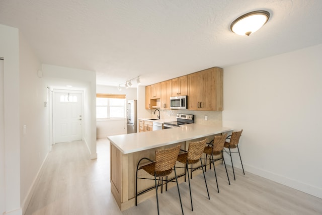 kitchen featuring sink, a breakfast bar area, tasteful backsplash, kitchen peninsula, and stainless steel appliances