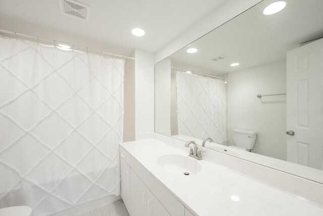 bathroom featuring vanity, toilet, and walk in shower