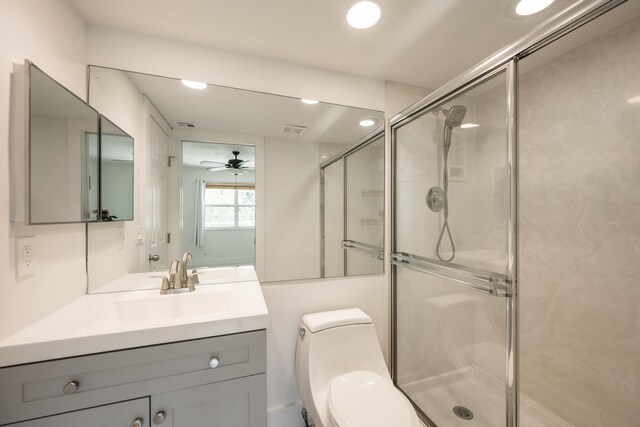 bathroom with ceiling fan, vanity, toilet, and a shower with door