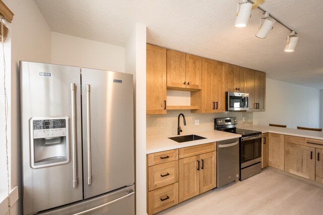 kitchen with tasteful backsplash, sink, light hardwood / wood-style flooring, and appliances with stainless steel finishes