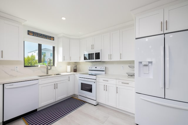 kitchen with white appliances, sink, and white cabinets