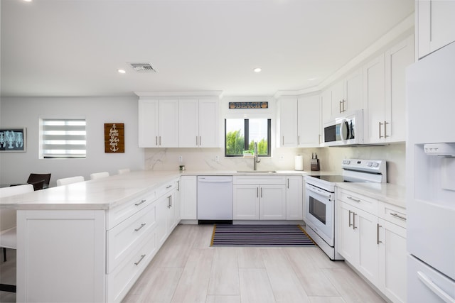 kitchen featuring sink, a breakfast bar area, kitchen peninsula, white appliances, and white cabinets