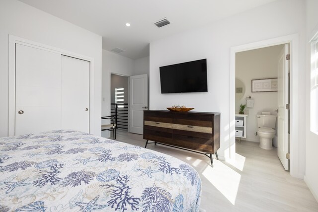 bedroom with connected bathroom, a closet, and light wood-type flooring