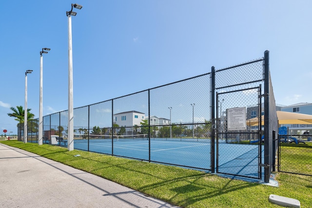 view of tennis court featuring a lawn