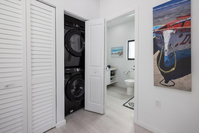 washroom with stacked washer and dryer and light wood-type flooring