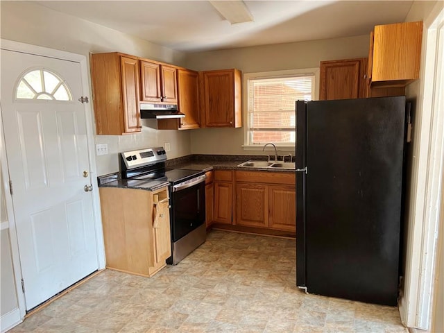 kitchen with under cabinet range hood, a sink, freestanding refrigerator, dark countertops, and stainless steel range with electric stovetop