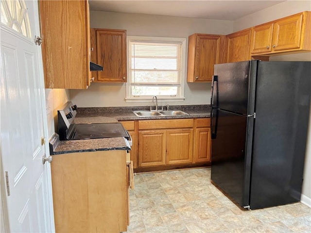 kitchen featuring stainless steel range with electric stovetop, dark countertops, a sink, and freestanding refrigerator