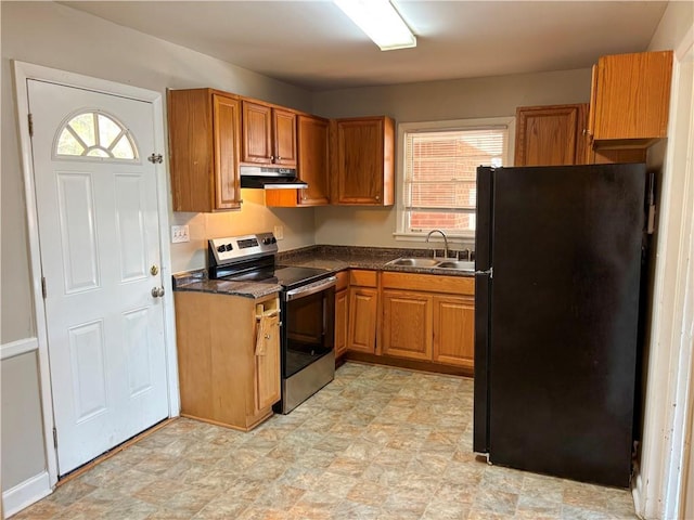 kitchen with electric stove, dark countertops, freestanding refrigerator, a sink, and under cabinet range hood