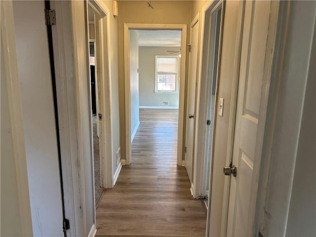 hall featuring wood finished floors, visible vents, and baseboards