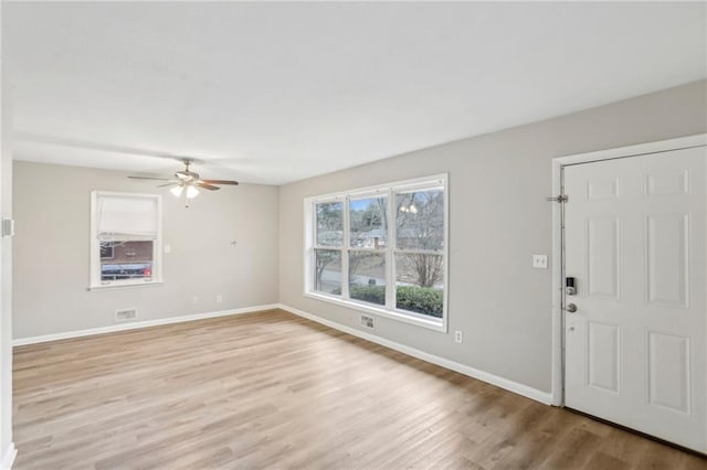 foyer with light wood-type flooring, visible vents, ceiling fan, and baseboards