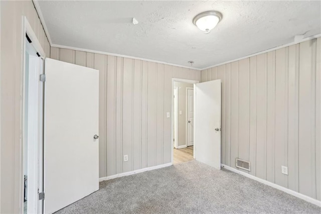 unfurnished bedroom with carpet, visible vents, and a textured ceiling