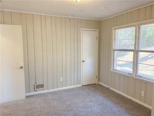 unfurnished room with ornamental molding, carpet, visible vents, and baseboards