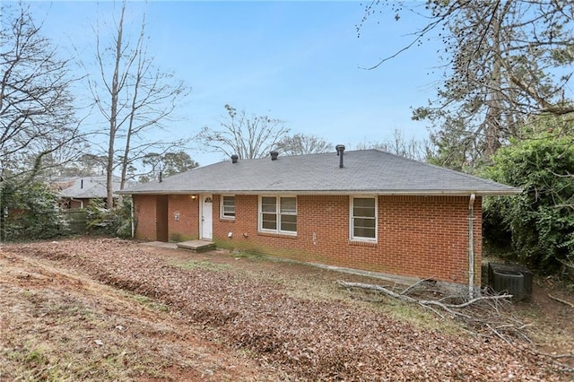 back of house featuring brick siding and central air condition unit