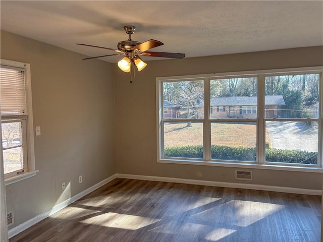 unfurnished room with baseboards, visible vents, and dark wood finished floors