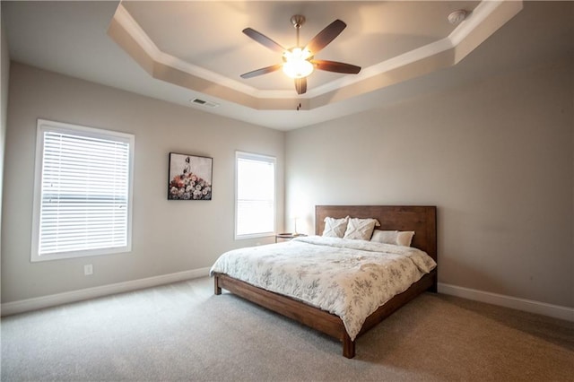 carpeted bedroom featuring ceiling fan and a raised ceiling