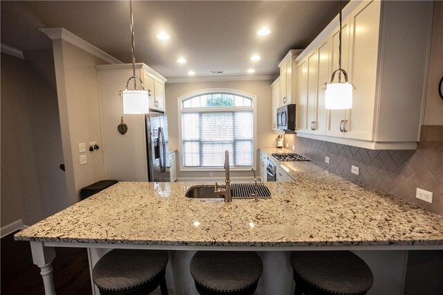 kitchen featuring sink, hanging light fixtures, stainless steel appliances, and a breakfast bar