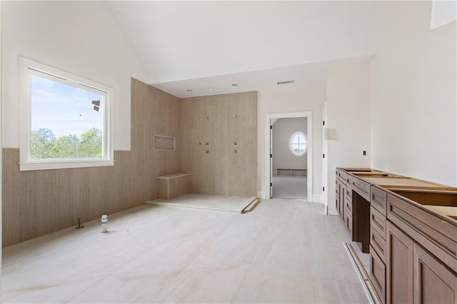 bathroom with lofted ceiling, visible vents, and a wainscoted wall