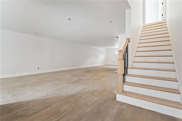 staircase featuring wood finished floors and baseboards