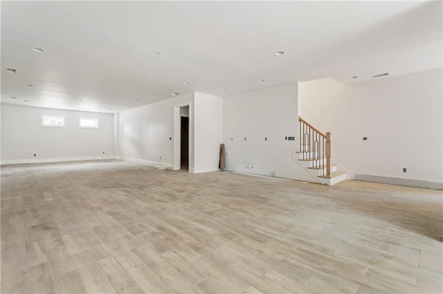 spare room featuring baseboards, light wood-style flooring, visible vents, and stairs