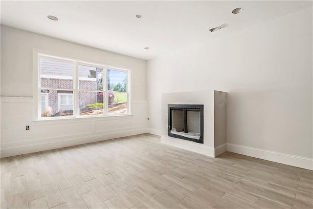 unfurnished living room featuring a fireplace, light wood-style flooring, and baseboards