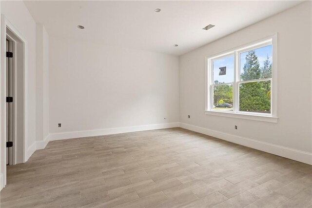 spare room with baseboards and light wood-style flooring