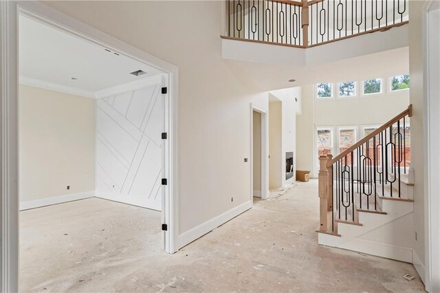 foyer entrance featuring baseboards, a high ceiling, stairway, and crown molding