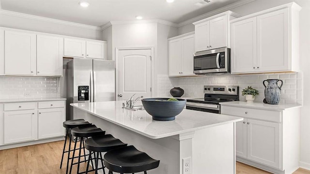 4954 Jatoba Rd Unit 72, Acworth, GA 30101 - kitchen featuring appliances with stainless steel finishes, a center island with sink, light wood finished floors, decorative backsplash, and white cabinets