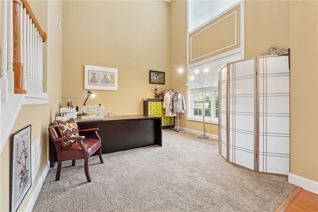 carpeted office space featuring baseboards and a towering ceiling