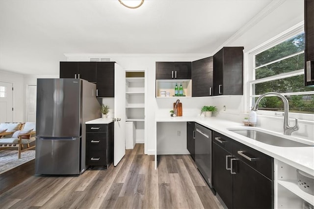 kitchen with ornamental molding, stainless steel appliances, sink, and light wood-type flooring