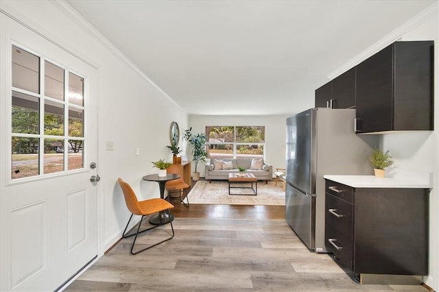 kitchen featuring stainless steel fridge, ornamental molding, and light hardwood / wood-style floors