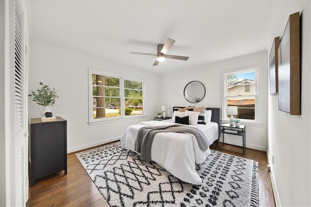 bedroom with multiple windows, ceiling fan, and dark hardwood / wood-style flooring