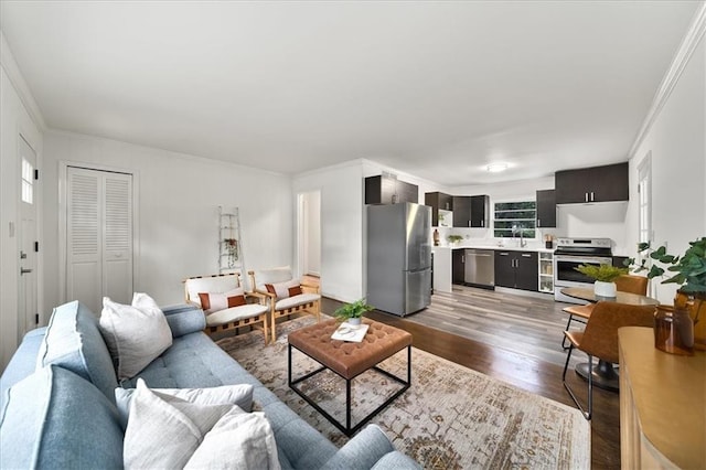 living room featuring hardwood / wood-style flooring, crown molding, and sink