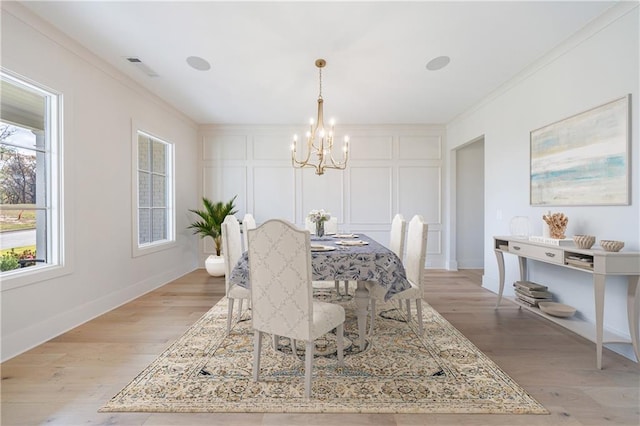 dining area with ornamental molding, a notable chandelier, and light wood-type flooring