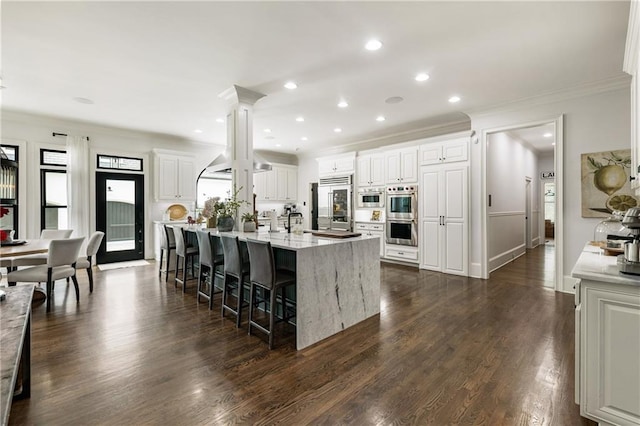 15595 Birmingham Hwy, Alpharetta, GA 30004 - kitchen with stainless steel appliances, ornamental molding, a spacious island, a breakfast bar area, and white cabinetry