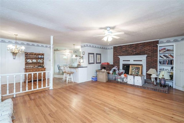 1526 N Cherokee Rd N, Social Circle, GA 30025 - living room featuring wood finished floors, a ceiling fan, a chandelier, a brick fireplace, and a textured ceiling