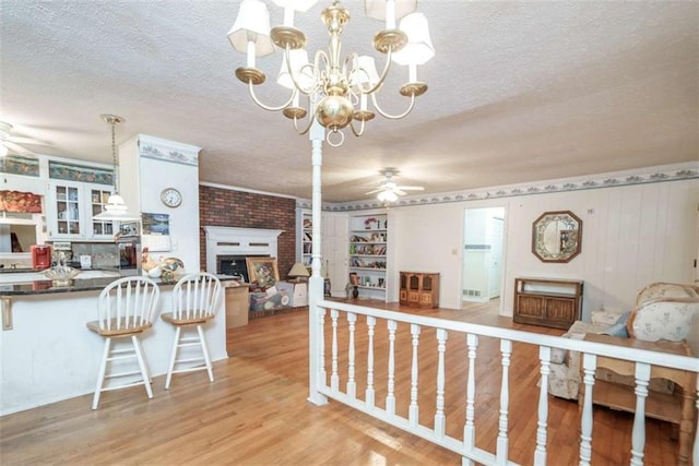 1526 N Cherokee Rd N, Social Circle, GA 30025 - interior space featuring a textured ceiling, ceiling fan, a large fireplace, light wood-style flooring, and a chandelier