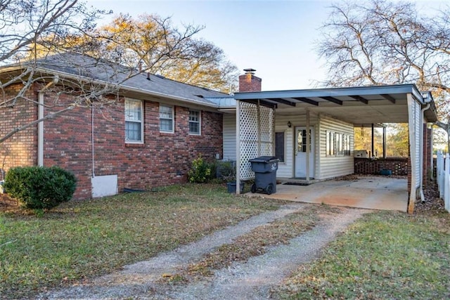 1526 N Cherokee Rd N, Social Circle, GA 30025 - view of home's exterior featuring a chimney, dirt driveway, brick siding, a carport, and a lawn