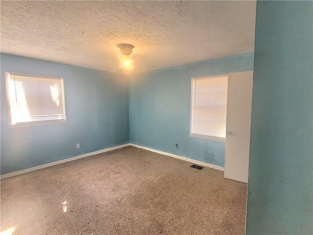 carpeted empty room with a textured ceiling