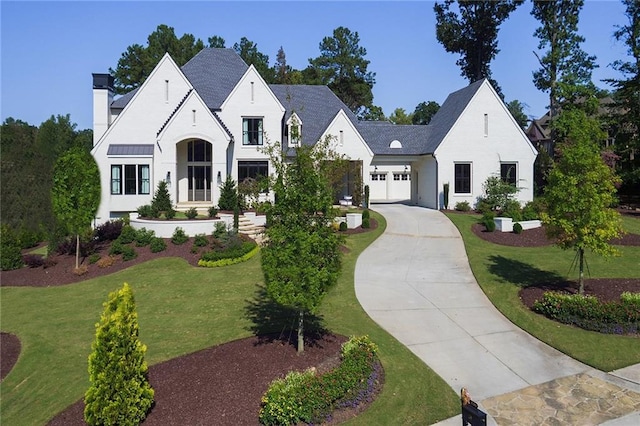 french country inspired facade featuring concrete driveway, a chimney, an attached garage, and a front yard