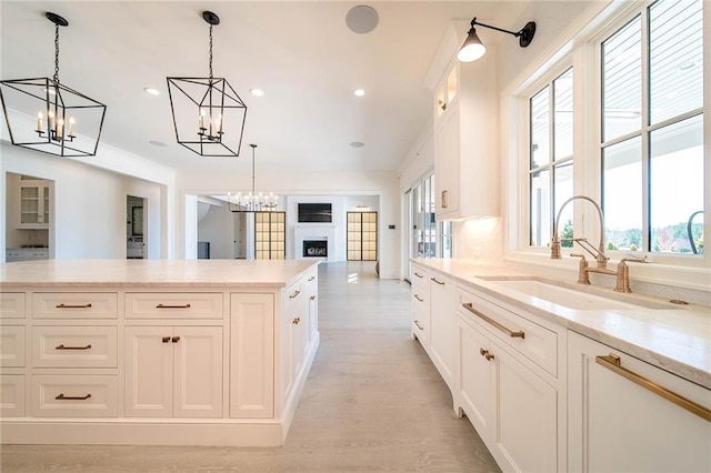 kitchen featuring a sink, a chandelier, open floor plan, white cabinets, and decorative light fixtures