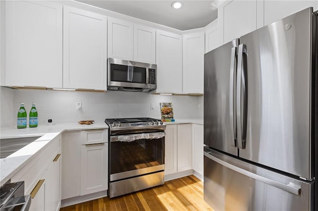 2453 Paul Ave NW, Atlanta, GA 30318 - kitchen with stainless steel appliances, light wood-type flooring, white cabinetry, tasteful backsplash, and light stone counters