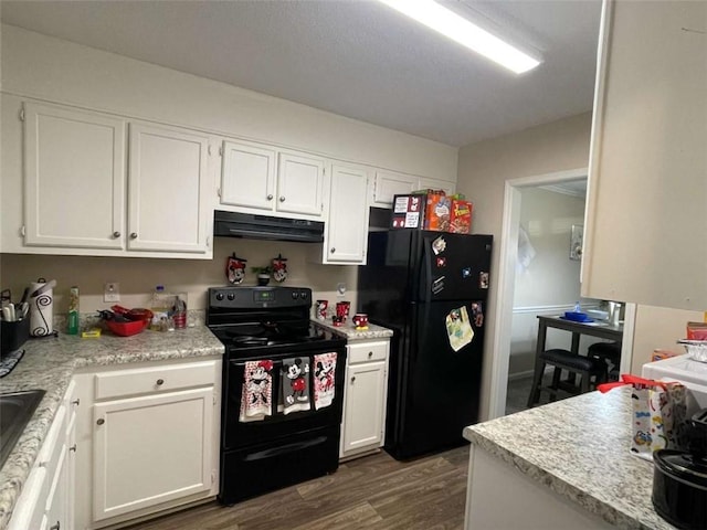 kitchen featuring dark wood finished floors, light countertops, white cabinets, under cabinet range hood, and black appliances