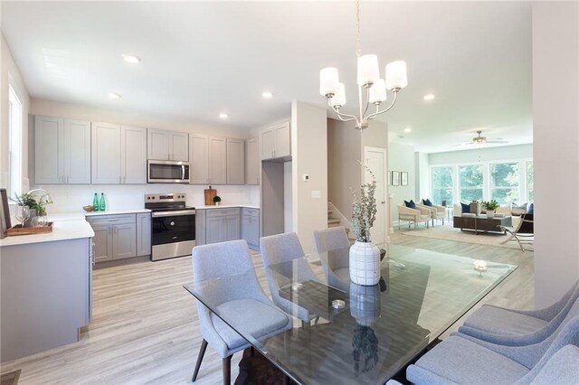 kitchen with light wood finished floors, stainless steel appliances, gray cabinets, light countertops, and a sink