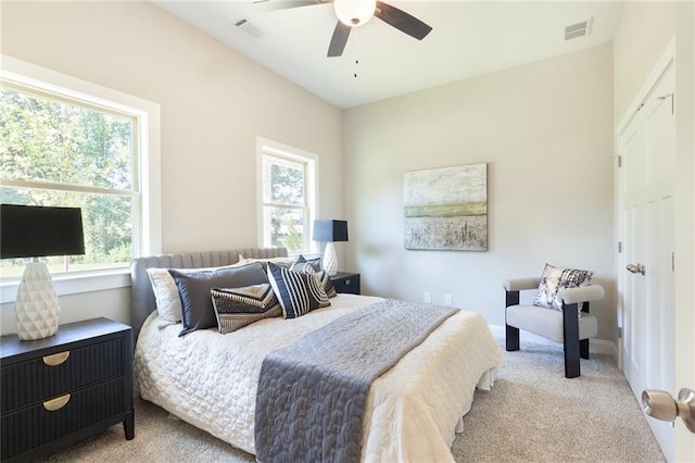 bedroom with light carpet, ceiling fan, visible vents, and baseboards