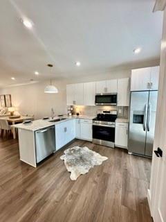 kitchen with sink, decorative light fixtures, dark hardwood / wood-style flooring, kitchen peninsula, and stainless steel appliances