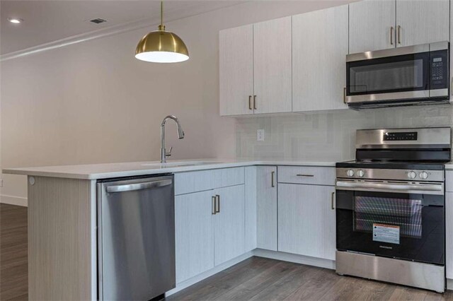 kitchen featuring light stone countertops, appliances with stainless steel finishes, dark hardwood / wood-style flooring, ornamental molding, and sink