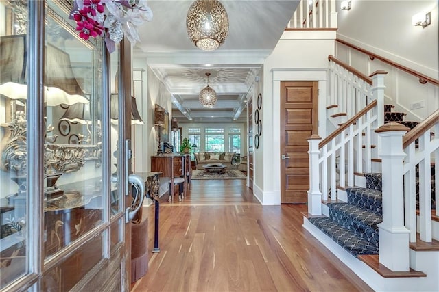 foyer entrance featuring ornamental molding, beam ceiling, coffered ceiling, and hardwood / wood-style floors